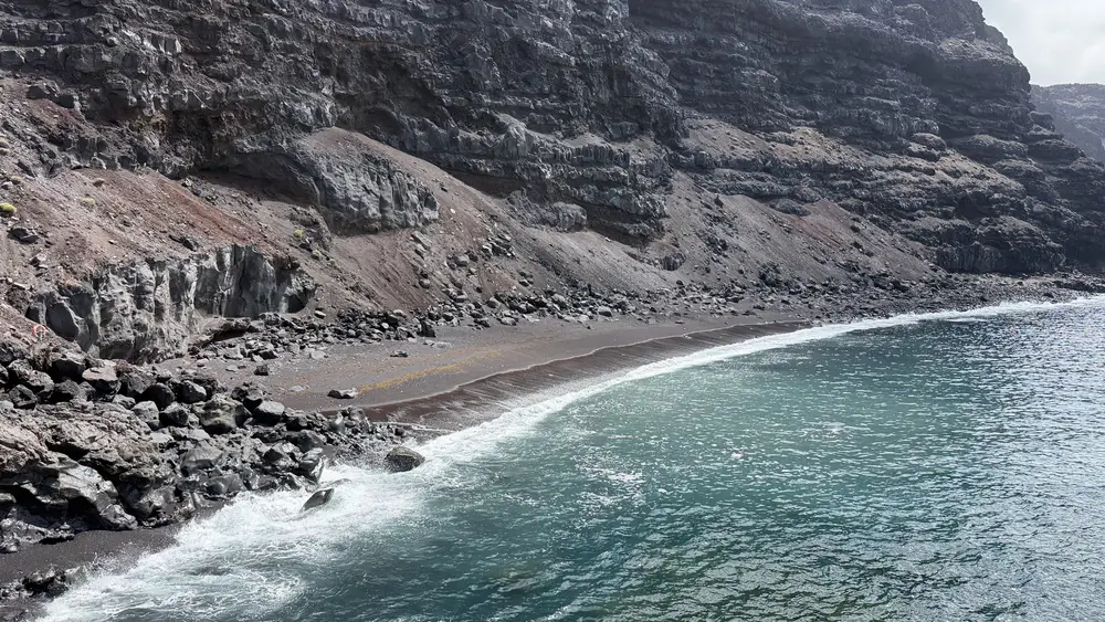 Playa de El Verodal con arena oscura y acantilados volcánicos en El Hierro